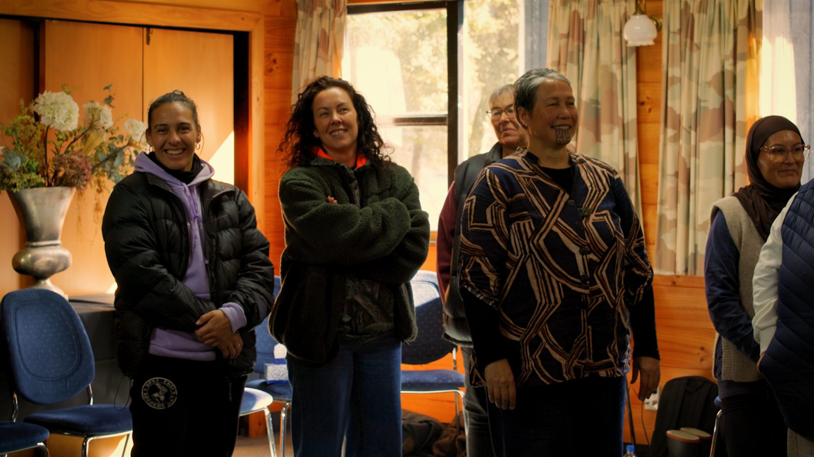 Whānau standing together in the wānanga room, smiling during a session
