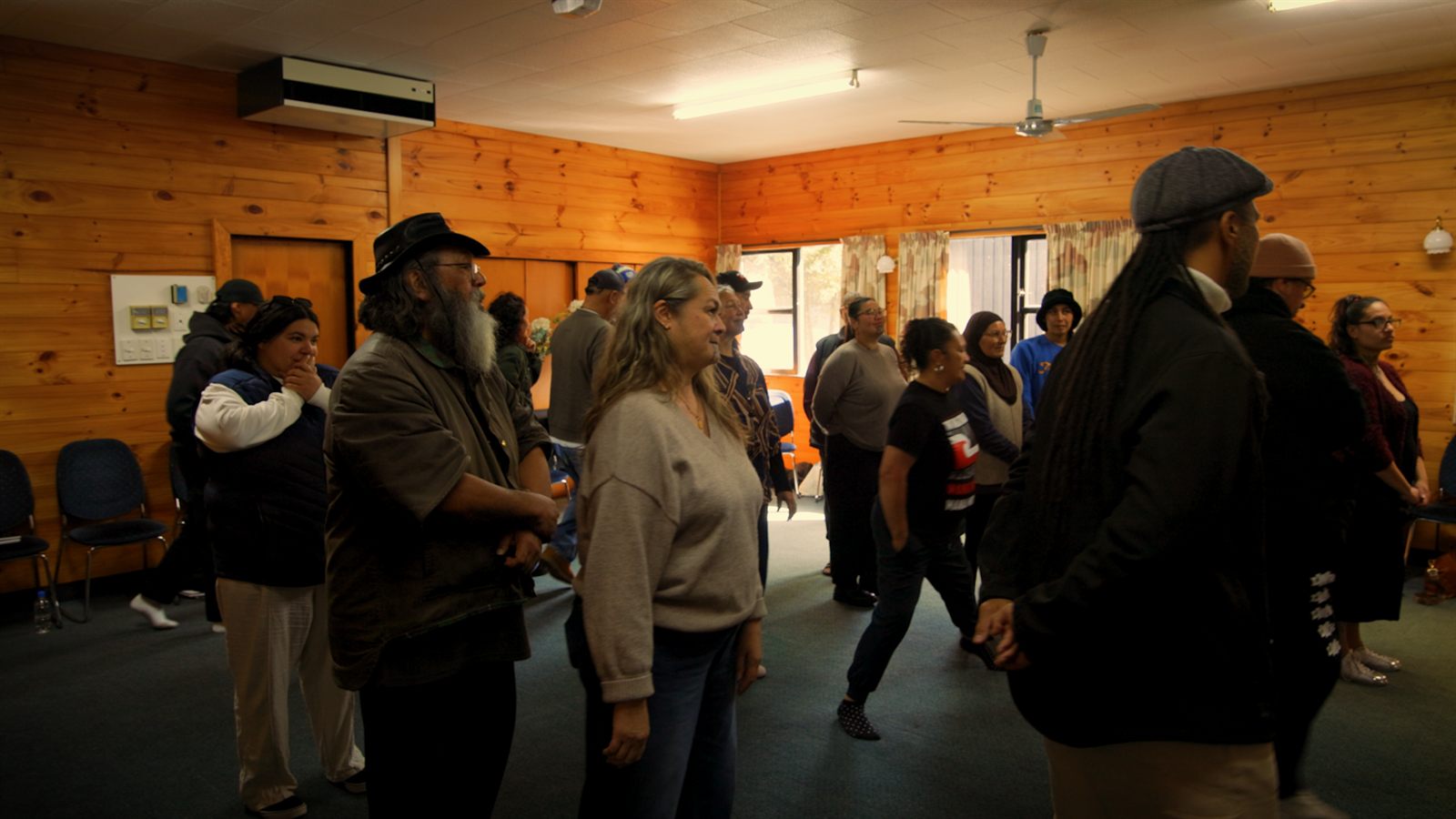 Whānau standing together in the wharenui at Okataina Lodge during Wānanga Tahi
